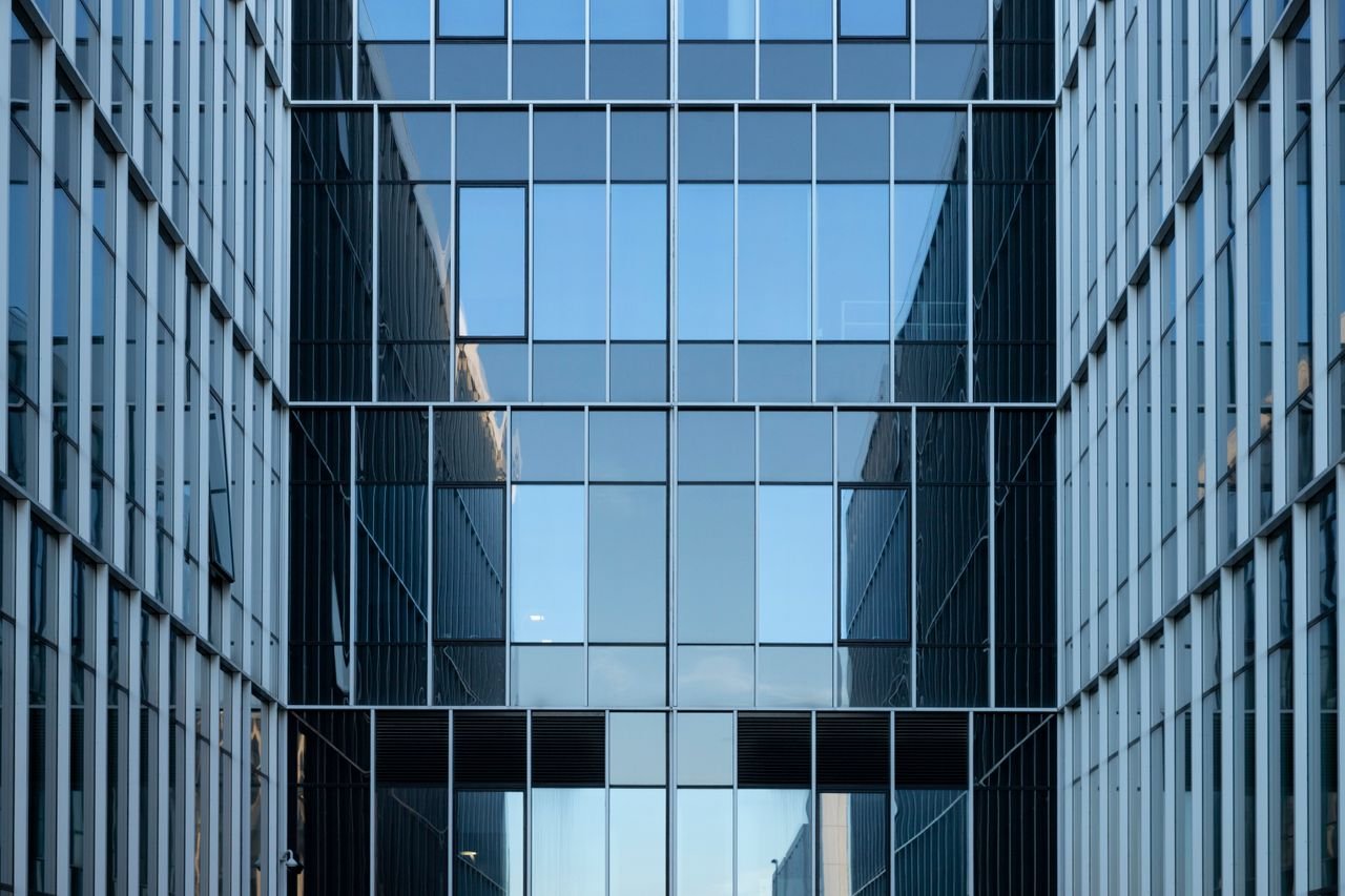 Contemporary building facade with reflective glass windows in an urban environment.