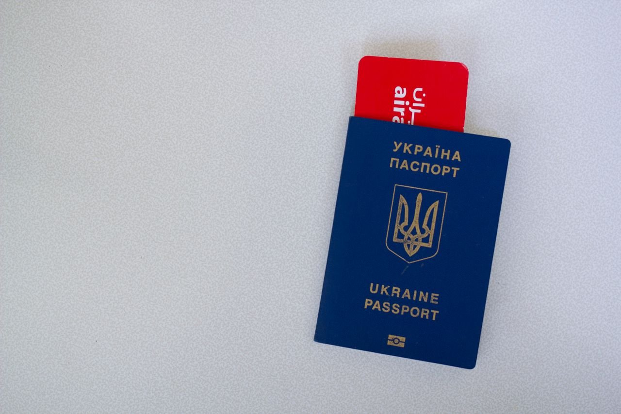 services-01 Close-up of a Ukrainian passport with an airline boarding pass on a white surface.